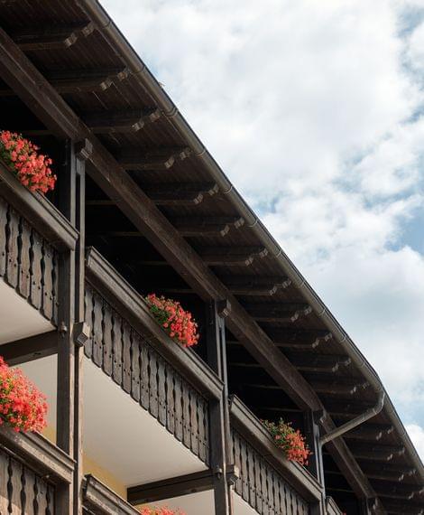 Holzbalkone mit roten Geranien an traditionellem Gebäude vor blauem Himmel