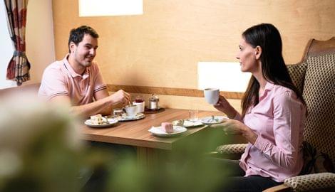 Paar trinkt Kaffee und isst Dessert in einem gemütlichen Café