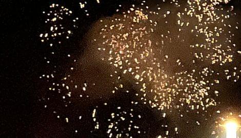 Feuerwerk mit goldenen Funken am Nachthimmel über einem beleuchteten Haus