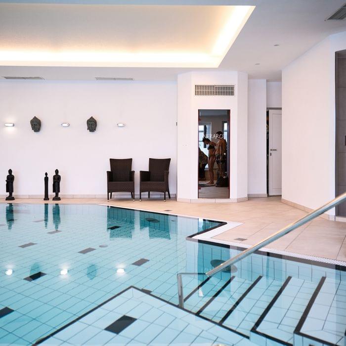 Innenpool mit Treppe, Buddha-Statuen und moderner Spa-Einrichtung im Wellnessbereich