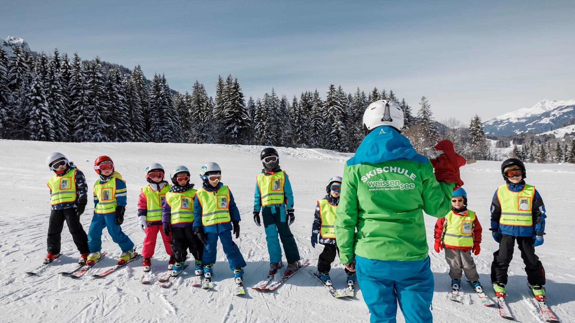 Skilehrer unterrichtet Kindergruppe in Skischule am verschneiten Hang in Weissensee