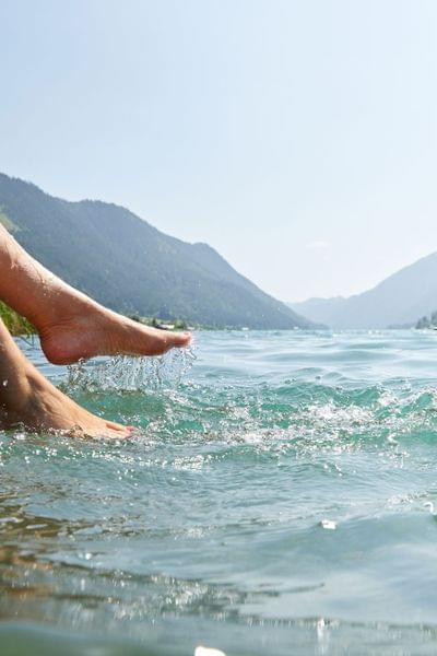 Beine planschen im klaren Wasser eines Bergsees an einem sonnigen Sommertag