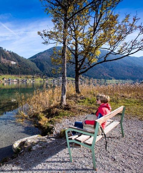 Frau macht eine Pause am Seeufer vom Weissensee beim Spazierengehen