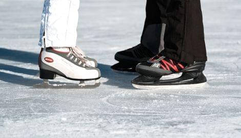 Zwei Personen mit weißen und schwarzen Eislaufschuhen stehen sich auf einer Eisfläche gegenüber